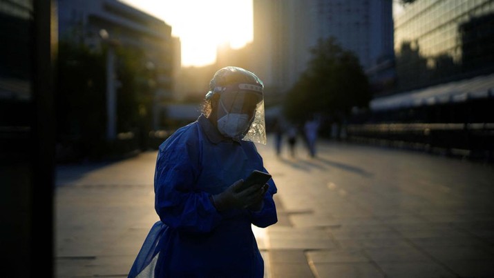 Seorang wanita dengan pakaian pelindung berjalan di dekat Stasiun Kereta Shanghai, setelah penguncian yang dilakukan untuk mengekang wabah penyakit virus corona (COVID-19). (REUTERS/ALY SONG)