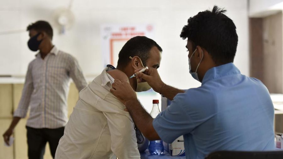 Seorang wanita berjalan melewati mural yang menggambarkan orang-orang yang mengenakan masker untuk menciptakan kesadaran tentang virus corona Covid-19 di Mumbai pada 8 Juni 2022. (AFP via Getty Images/PUNIT PARANJPE)