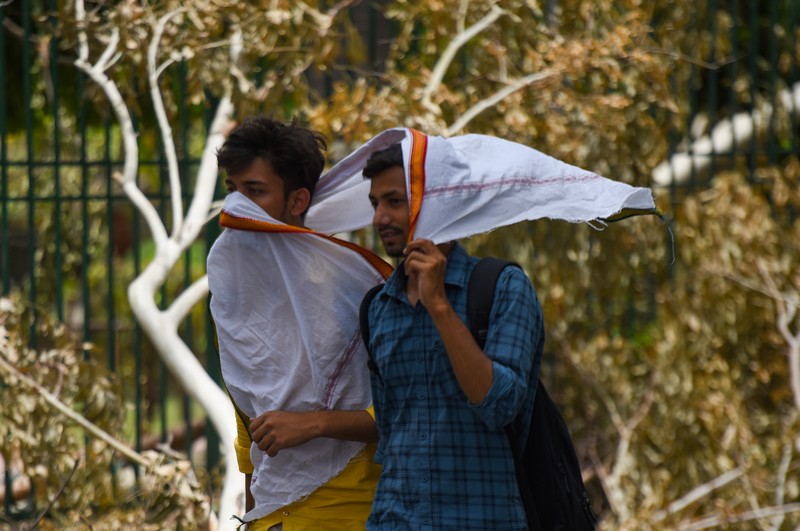 Seorang wanita berjalan melewati mural yang menggambarkan orang-orang yang mengenakan masker untuk menciptakan kesadaran tentang virus corona Covid-19 di Mumbai pada 8 Juni 2022. (AFP via Getty Images/PUNIT PARANJPE)