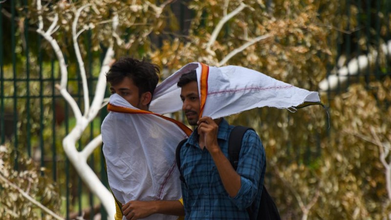 Seorang wanita berjalan melewati mural yang menggambarkan orang-orang yang mengenakan masker untuk menciptakan kesadaran tentang virus corona Covid-19 di Mumbai pada 8 Juni 2022. (AFP via Getty Images/PUNIT PARANJPE)