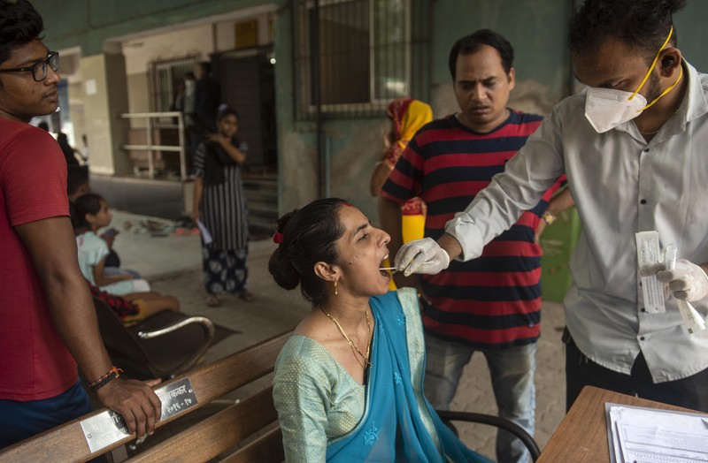 Seorang wanita berjalan melewati mural yang menggambarkan orang-orang yang mengenakan masker untuk menciptakan kesadaran tentang virus corona Covid-19 di Mumbai pada 8 Juni 2022. (AFP via Getty Images/PUNIT PARANJPE)