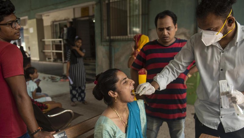 Seorang wanita berjalan melewati mural yang menggambarkan orang-orang yang mengenakan masker untuk menciptakan kesadaran tentang virus corona Covid-19 di Mumbai pada 8 Juni 2022. (AFP via Getty Images/PUNIT PARANJPE)