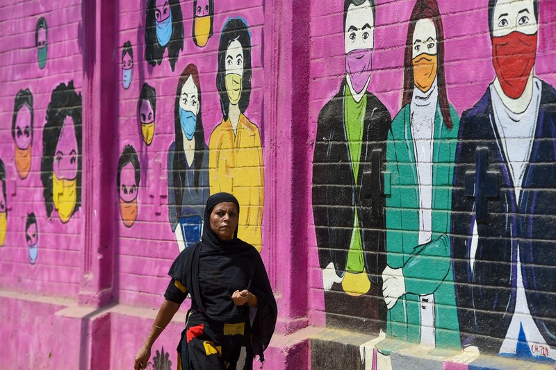 Seorang wanita berjalan melewati mural yang menggambarkan orang-orang yang mengenakan masker untuk menciptakan kesadaran tentang virus corona Covid-19 di Mumbai pada 8 Juni 2022. (AFP via Getty Images/PUNIT PARANJPE) Seorang wanita berjalan melewati mural yang menggambarkan orang-orang yang mengenakan masker untuk menciptakan kesadaran tentang virus corona Covid-19 di Mumbai pada 8 Juni 2022. (AFP via Getty Images/PUNIT PARANJPE)
