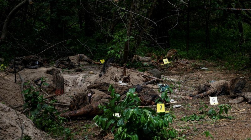 Tim forensik memasukkan ke dalam kantong jenazah tubuh seseorang yang diduga dibunuh dan dikuburkan selama serangan Rusia ke Ukraina di dekat desa Vorzel di distrik Bucha, wilayah Kyiv, Ukraina, Senin (13/6/2022). (REUTERS/Valentyn Ogirenko)