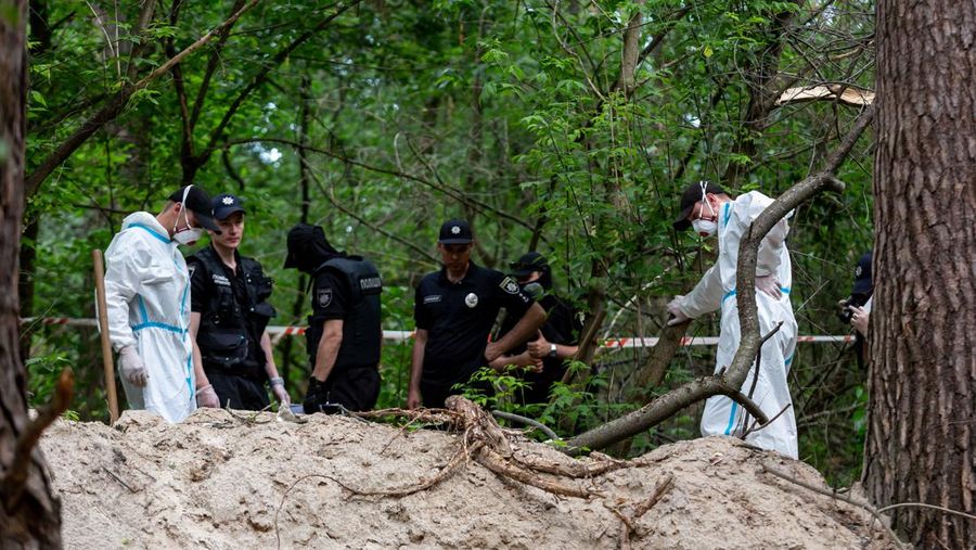 Tim forensik memasukkan ke dalam kantong jenazah tubuh seseorang yang diduga dibunuh dan dikuburkan selama serangan Rusia ke Ukraina di dekat desa Vorzel di distrik Bucha, wilayah Kyiv, Ukraina, Senin (13/6/2022). (REUTERS/Valentyn Ogirenko)