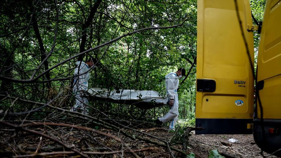 Tim forensik memasukkan ke dalam kantong jenazah tubuh seseorang yang diduga dibunuh dan dikuburkan selama serangan Rusia ke Ukraina di dekat desa Vorzel di distrik Bucha, wilayah Kyiv, Ukraina, Senin (13/6/2022). (REUTERS/Valentyn Ogirenko)
