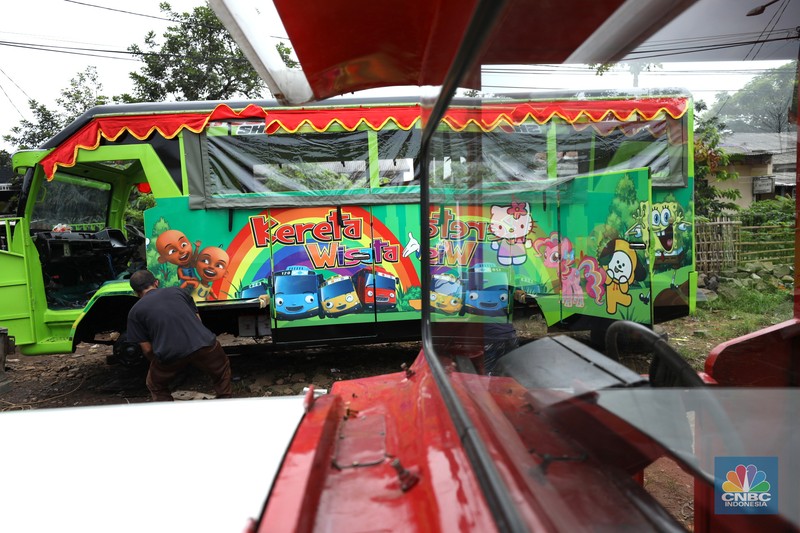 Pekerja menyelesaikan pembuatan mobil odong-odong di kawasan Pondok Aren, Tangerang Selatan, Banten, Selasa (14/6/2022). Di workshop ini mobil lama dan hanya menyisakan mesin beserta sasisnya lalu dirakit ulang menjadi kereta wisata mini atau yang biasa disebut dengan odong-odong. (CNBC Indonesia/ Tri Susilo)