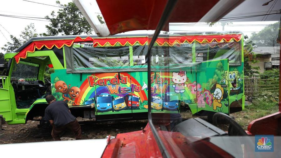 Pekerja menyelesaikan pembuatan mobil odong-odong di kawasan Pondok Aren, Tangerang Selatan, Banten, Selasa (14/6/2022). Di workshop ini mobil lama dan hanya menyisakan mesin beserta sasisnya lalu dirakit ulang menjadi kereta wisata mini atau yang biasa disebut dengan odong-odong. (CNBC Indonesia/ Tri Susilo)