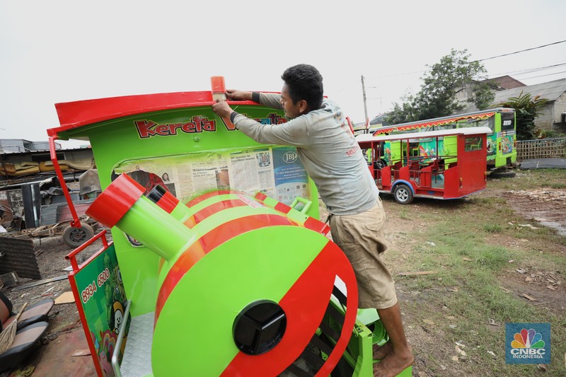 Pekerja menyelesaikan pembuatan mobil odong-odong di kawasan Pondok Aren, Tangerang Selatan, Banten, Selasa (14/6/2022). Di workshop ini mobil lama dan hanya menyisakan mesin beserta sasisnya lalu dirakit ulang menjadi kereta wisata mini atau yang biasa disebut dengan odong-odong. (CNBC Indonesia/ Tri Susilo)