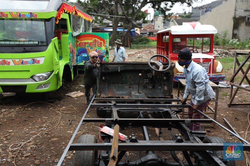 Pekerja menyelesaikan pembuatan mobil odong-odong di kawasan Pondok Aren, Tangerang Selatan, Banten, Selasa (14/6/2022). Di workshop ini mobil lama dan hanya menyisakan mesin beserta sasisnya lalu dirakit ulang menjadi kereta wisata mini atau yang biasa disebut dengan odong-odong. (CNBC Indonesia/ Tri Susilo)