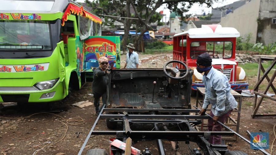 Pekerja menyelesaikan pembuatan mobil odong-odong di kawasan Pondok Aren, Tangerang Selatan, Banten, Selasa (14/6/2022). Di workshop ini mobil lama dan hanya menyisakan mesin beserta sasisnya lalu dirakit ulang menjadi kereta wisata mini atau yang biasa disebut dengan odong-odong. (CNBC Indonesia/ Tri Susilo)
