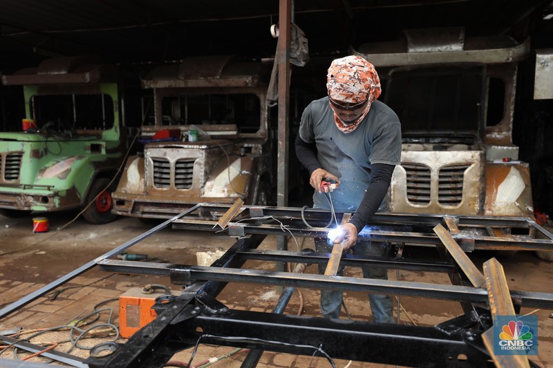 Pekerja menyelesaikan pembuatan mobil odong-odong di kawasan Pondok Aren, Tangerang Selatan, Banten, Selasa (14/6/2022). Di workshop ini mobil lama dan hanya menyisakan mesin beserta sasisnya lalu dirakit ulang menjadi kereta wisata mini atau yang biasa disebut dengan odong-odong. (CNBC Indonesia/ Tri Susilo)