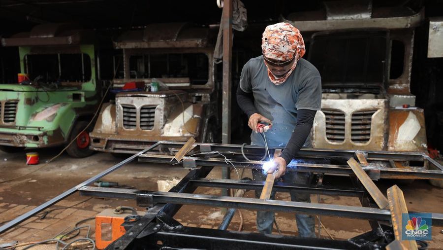 Pekerja menyelesaikan pembuatan mobil odong-odong di kawasan Pondok Aren, Tangerang Selatan, Banten, Selasa (14/6/2022). Di workshop ini mobil lama dan hanya menyisakan mesin beserta sasisnya lalu dirakit ulang menjadi kereta wisata mini atau yang biasa disebut dengan odong-odong. (CNBC Indonesia/ Tri Susilo)