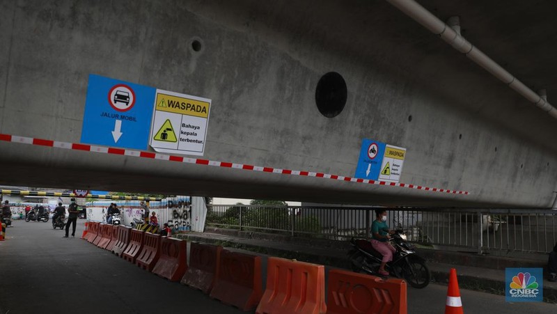 Petugas mengatur lalu lintas kendaraan yang melintas di Jembatan Antelope, Curug, Bekasi, Jawa Barat, Selasa (14/6/2022). Pengaturan lalu lintas karena adanya pemasangan girder proyek kereta cepat dan hanya dapat dilalui kendaraan dengan ketinggian maksimal 1,7 meter dari tanggal 13 Juni hingga 10 Agustus 2022. (CNBC Indonesia/ Muhammad Sabki)