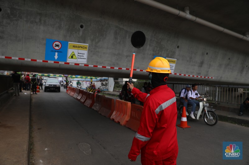 Petugas mengatur lalu lintas kendaraan yang melintas di Jembatan Antelope, Curug, Bekasi, Jawa Barat, Selasa (14/6/2022). Pengaturan lalu lintas karena adanya pemasangan girder proyek kereta cepat dan hanya dapat dilalui kendaraan dengan ketinggian maksimal 1,7 meter dari tanggal 13 Juni hingga 10 Agustus 2022. (CNBC Indonesia/ Muhammad Sabki)
