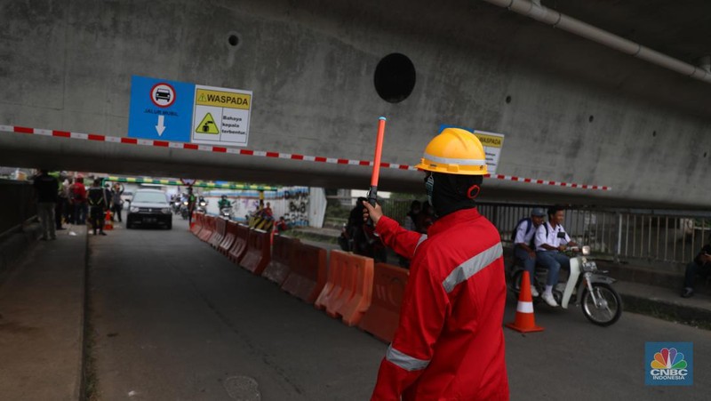 Petugas mengatur lalu lintas kendaraan yang melintas di Jembatan Antelope, Curug, Bekasi, Jawa Barat, Selasa (14/6/2022). Pengaturan lalu lintas karena adanya pemasangan girder proyek kereta cepat dan hanya dapat dilalui kendaraan dengan ketinggian maksimal 1,7 meter dari tanggal 13 Juni hingga 10 Agustus 2022. (CNBC Indonesia/ Muhammad Sabki)