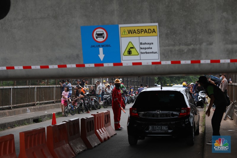 Penampakan Girder Jalur Kereta Cepat Halangi Jalanan di Jembatan Antelope, Curug, Bekasi, Petugas mengatur lalu lintas kendaraan yang melintas di Jembatan Antelope, Curug, Bekasi, Jawa Barat, Selasa (14/6/2022). Pengaturan lalu lintas karena adanya pemasangan girder proyek kereta cepat dan hanya dapat dilalui kendaraan dengan ketinggian maksimal 1,7 meter dari tanggal 13 Juni hingga 10 Agustus 2022. (CNBC Indonesia/ Muhammad Sabki)