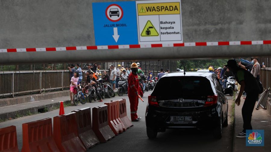 Petugas mengatur lalu lintas kendaraan yang melintas di Jembatan Antelope, Curug, Bekasi, Jawa Barat, Selasa (14/6/2022). Pengaturan lalu lintas karena adanya pemasangan girder proyek kereta cepat dan hanya dapat dilalui kendaraan dengan ketinggian maksimal 1,7 meter dari tanggal 13 Juni hingga 10 Agustus 2022. (CNBC Indonesia/ Muhammad Sabki)