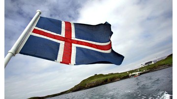 Bendera Islandia Iceland flag flaps on October 13, 2008 as a boat leaves the Videy Island. Videy is the largest island of the Kollafjord Bay (1,7 km²) with its highest point rising 32 m above sea level. It is divided by a short isthmus and the western part is called The West Island. AFP PHOTO/Thorvaldur Orn Krismundsson (Photo by - / AFP) (Photo by -/AFP via Getty Images)