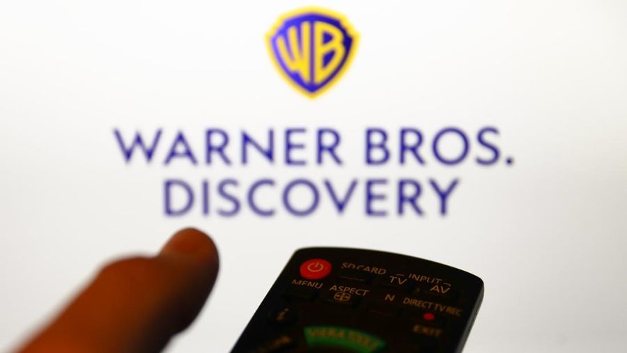 Warner Bros. Discovery logo displayed on a screen and a tv remote control are seen in this illustration photo taken in Krakow, Poland on April 9, 2022. (Photo by Jakub Porzycki/NurPhoto via Getty Images)