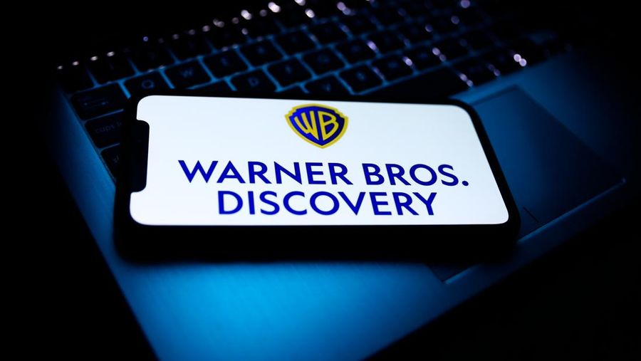 Warner Bros. Discovery logo displayed on a phone screen and a laptop keyboard are seen in this illustration photo taken in Krakow, Poland on April 9, 2022. (Photo by Jakub Porzycki/NurPhoto via Getty Images)