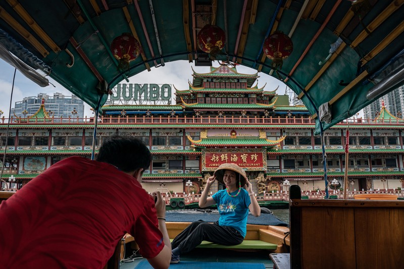 Turis mengambil foto di depan Restoran Terapung Jumbo bergaya kekaisaran China di Aberdeen, Hong Kong, Senin (13/6/2022). Restoran Terapung Jumbo yang ikonik di Hong Kong akan meninggalkan kota, di tengah kurangnya dana untuk memelihara restoran setelah berbulan-bulan pembatasan COVID-19. (Photo by Anthony Kwan/Getty Images)