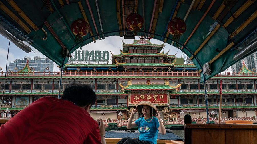 Turis mengambil foto di depan Restoran Terapung Jumbo bergaya kekaisaran China di Aberdeen, Hong Kong, Senin (13/6/2022). Restoran Terapung Jumbo yang ikonik di Hong Kong akan meninggalkan kota, di tengah kurangnya dana untuk memelihara restoran setelah berbulan-bulan pembatasan COVID-19. (Photo by Anthony Kwan/Getty Images)