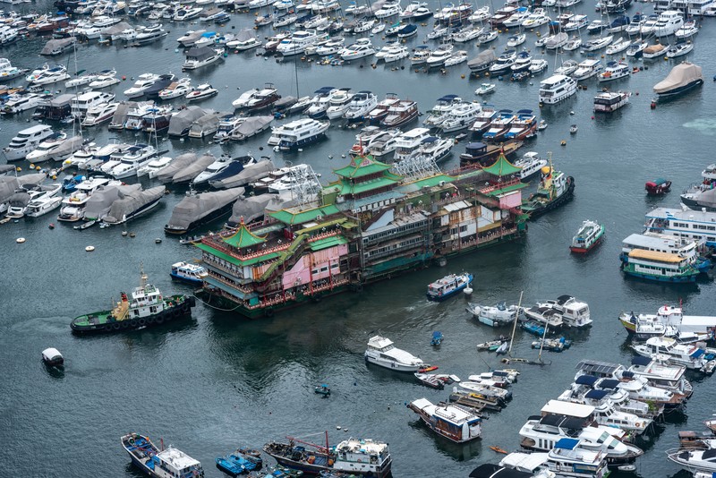 Turis mengambil foto di depan Restoran Terapung Jumbo bergaya kekaisaran China di Aberdeen, Hong Kong, Senin (13/6/2022). Restoran Terapung Jumbo yang ikonik di Hong Kong akan meninggalkan kota, di tengah kurangnya dana untuk memelihara restoran setelah berbulan-bulan pembatasan COVID-19. (Photo by Anthony Kwan/Getty Images)