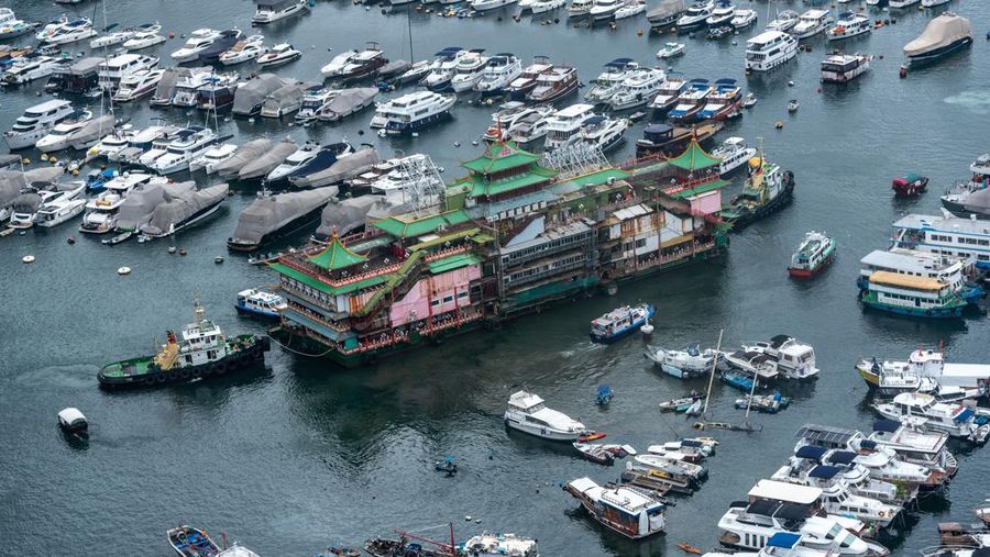 Turis mengambil foto di depan Restoran Terapung Jumbo bergaya kekaisaran China di Aberdeen, Hong Kong, Senin (13/6/2022). Restoran Terapung Jumbo yang ikonik di Hong Kong akan meninggalkan kota, di tengah kurangnya dana untuk memelihara restoran setelah berbulan-bulan pembatasan COVID-19. (Photo by Anthony Kwan/Getty Images)