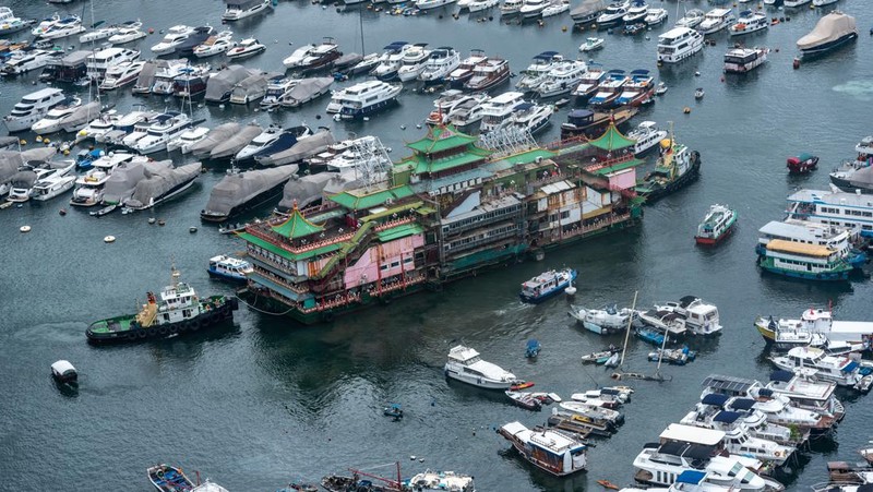 Turis mengambil foto di depan Restoran Terapung Jumbo bergaya kekaisaran China di Aberdeen, Hong Kong, Senin (13/6/2022). Restoran Terapung Jumbo yang ikonik di Hong Kong akan meninggalkan kota, di tengah kurangnya dana untuk memelihara restoran setelah berbulan-bulan pembatasan COVID-19. (Photo by Anthony Kwan/Getty Images)