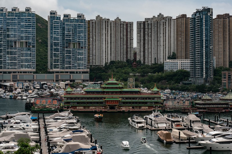 Turis mengambil foto di depan Restoran Terapung Jumbo bergaya kekaisaran China di Aberdeen, Hong Kong, Senin (13/6/2022). Restoran Terapung Jumbo yang ikonik di Hong Kong akan meninggalkan kota, di tengah kurangnya dana untuk memelihara restoran setelah berbulan-bulan pembatasan COVID-19. (Photo by Anthony Kwan/Getty Images)