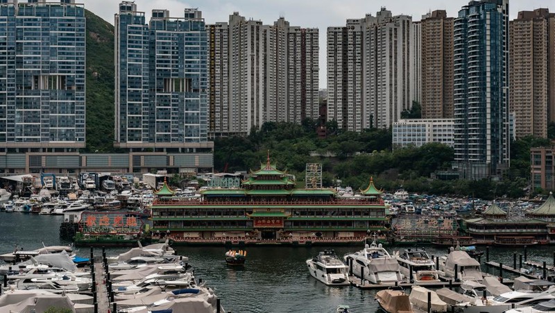 Turis mengambil foto di depan Restoran Terapung Jumbo bergaya kekaisaran China di Aberdeen, Hong Kong, Senin (13/6/2022). Restoran Terapung Jumbo yang ikonik di Hong Kong akan meninggalkan kota, di tengah kurangnya dana untuk memelihara restoran setelah berbulan-bulan pembatasan COVID-19. (Photo by Anthony Kwan/Getty Images)