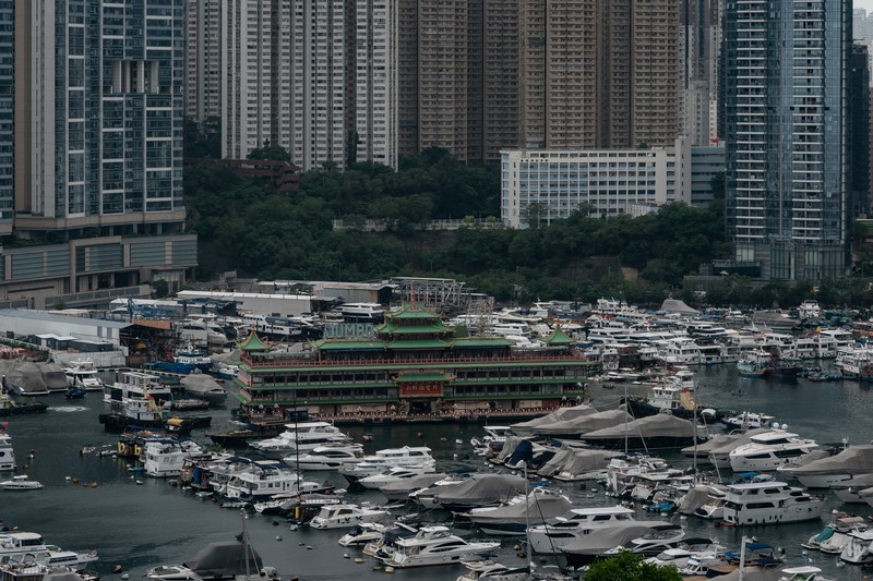 Turis mengambil foto di depan Restoran Terapung Jumbo bergaya kekaisaran China di Aberdeen, Hong Kong, Senin (13/6/2022). Restoran Terapung Jumbo yang ikonik di Hong Kong akan meninggalkan kota, di tengah kurangnya dana untuk memelihara restoran setelah berbulan-bulan pembatasan COVID-19. (Photo by Anthony Kwan/Getty Images)