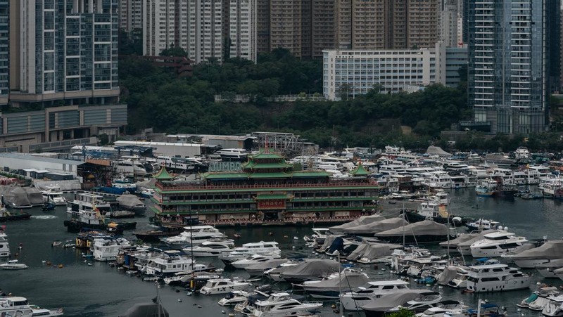 Turis mengambil foto di depan Restoran Terapung Jumbo bergaya kekaisaran China di Aberdeen, Hong Kong, Senin (13/6/2022). Restoran Terapung Jumbo yang ikonik di Hong Kong akan meninggalkan kota, di tengah kurangnya dana untuk memelihara restoran setelah berbulan-bulan pembatasan COVID-19. (Photo by Anthony Kwan/Getty Images)