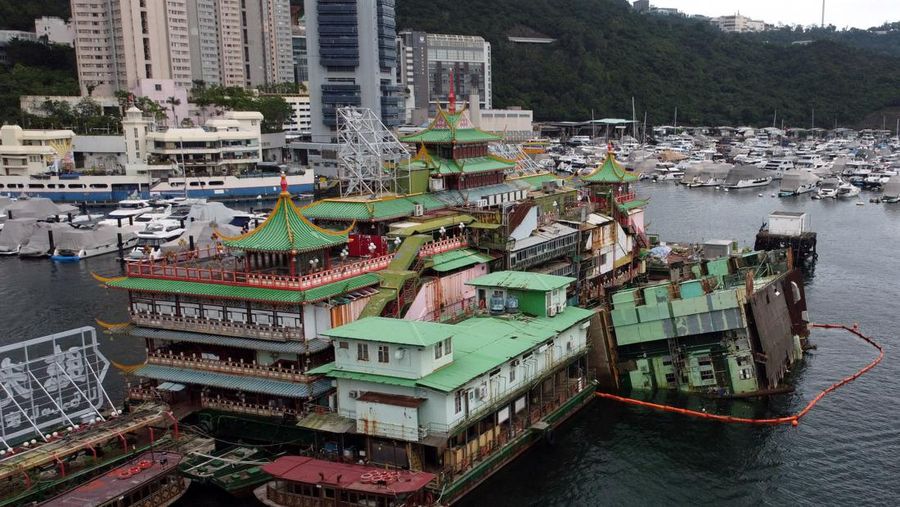 Turis mengambil foto di depan Restoran Terapung Jumbo bergaya kekaisaran China di Aberdeen, Hong Kong, Senin (13/6/2022). Restoran Terapung Jumbo yang ikonik di Hong Kong akan meninggalkan kota, di tengah kurangnya dana untuk memelihara restoran setelah berbulan-bulan pembatasan COVID-19. (Photo by Anthony Kwan/Getty Images)