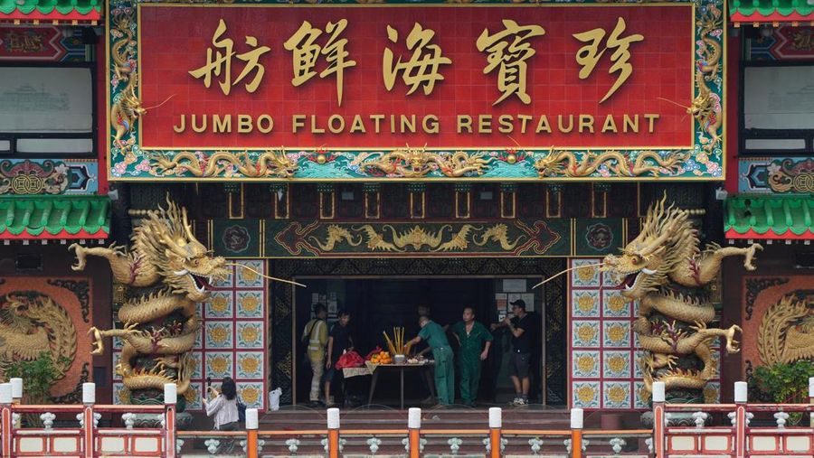 Turis mengambil foto di depan Restoran Terapung Jumbo bergaya kekaisaran China di Aberdeen, Hong Kong, Senin (13/6/2022). Restoran Terapung Jumbo yang ikonik di Hong Kong akan meninggalkan kota, di tengah kurangnya dana untuk memelihara restoran setelah berbulan-bulan pembatasan COVID-19. (Photo by Anthony Kwan/Getty Images)