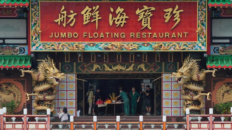 Turis mengambil foto di depan Restoran Terapung Jumbo bergaya kekaisaran China di Aberdeen, Hong Kong, Senin (13/6/2022). Restoran Terapung Jumbo yang ikonik di Hong Kong akan meninggalkan kota, di tengah kurangnya dana untuk memelihara restoran setelah berbulan-bulan pembatasan COVID-19. (Photo by Anthony Kwan/Getty Images)