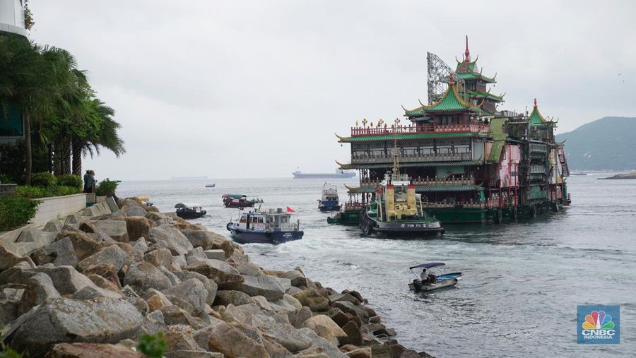 Turis mengambil foto di depan Restoran Terapung Jumbo bergaya kekaisaran China di Aberdeen, Hong Kong, Senin (13/6/2022). Restoran Terapung Jumbo yang ikonik di Hong Kong akan meninggalkan kota, di tengah kurangnya dana untuk memelihara restoran setelah berbulan-bulan pembatasan COVID-19. (Photo by Anthony Kwan/Getty Images)