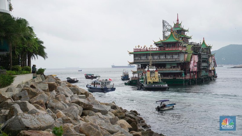 Turis mengambil foto di depan Restoran Terapung Jumbo bergaya kekaisaran China di Aberdeen, Hong Kong, Senin (13/6/2022). Restoran Terapung Jumbo yang ikonik di Hong Kong akan meninggalkan kota, di tengah kurangnya dana untuk memelihara restoran setelah berbulan-bulan pembatasan COVID-19. (Photo by Anthony Kwan/Getty Images)