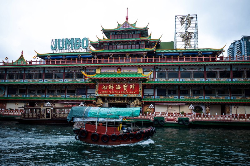 Turis mengambil foto di depan Restoran Terapung Jumbo bergaya kekaisaran China di Aberdeen, Hong Kong, Senin (13/6/2022). Restoran Terapung Jumbo yang ikonik di Hong Kong akan meninggalkan kota, di tengah kurangnya dana untuk memelihara restoran setelah berbulan-bulan pembatasan COVID-19. (Photo by Anthony Kwan/Getty Images)