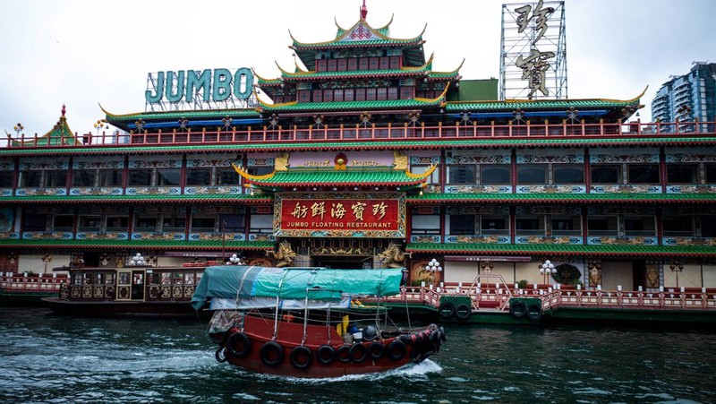 Turis mengambil foto di depan Restoran Terapung Jumbo bergaya kekaisaran China di Aberdeen, Hong Kong, Senin (13/6/2022). Restoran Terapung Jumbo yang ikonik di Hong Kong akan meninggalkan kota, di tengah kurangnya dana untuk memelihara restoran setelah berbulan-bulan pembatasan COVID-19. (Photo by Anthony Kwan/Getty Images)
