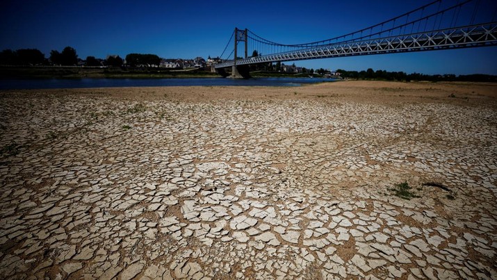 Tanah retak dan kering terlihat di dasar Sungai Loire dekat jembatan Anjou-Bretagne saat gelombang panas melanda Eropa, di Ancenis-Saint-Geron, Prancis, Senin (13/6/20222). (REUTERS/Stephane Mahe)