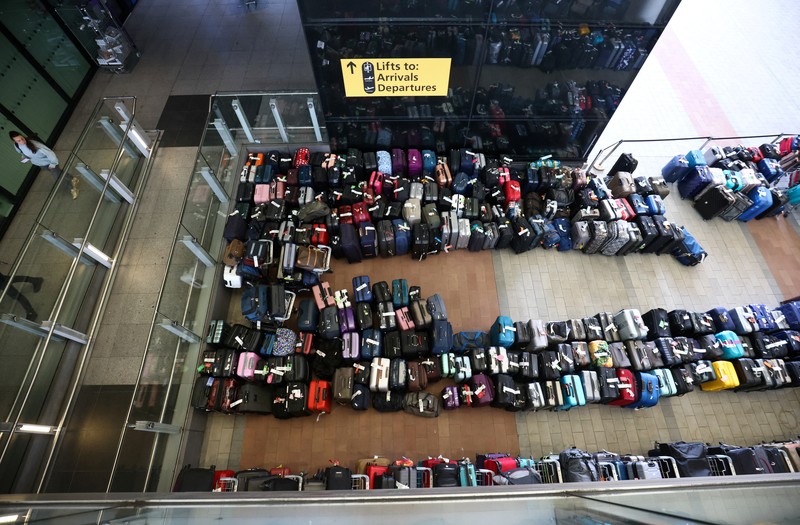 Airport workers stand next to lines of passenger luggage arranged outside Terminal 2 at Heathrow Airport in London, Britain, June 19, 2022. REUTERS/Henry Nicholls