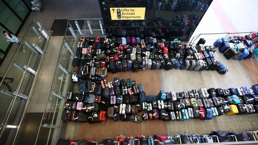 Airport workers stand next to lines of passenger luggage arranged outside Terminal 2 at Heathrow Airport in London, Britain, June 19, 2022. REUTERS/Henry Nicholls
