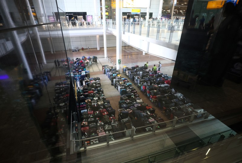Airport workers stand next to lines of passenger luggage arranged outside Terminal 2 at Heathrow Airport in London, Britain, June 19, 2022. REUTERS/Henry Nicholls
