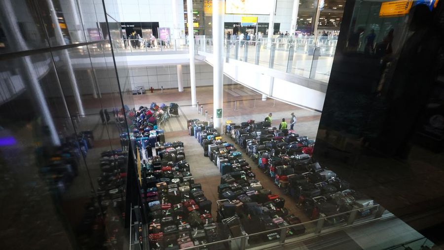 Airport workers stand next to lines of passenger luggage arranged outside Terminal 2 at Heathrow Airport in London, Britain, June 19, 2022. REUTERS/Henry Nicholls
