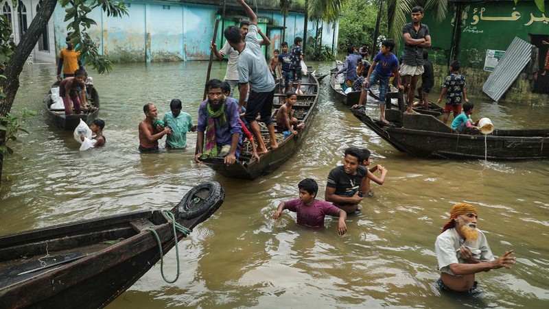 People gather to collect food aid in a flooded residential area following heavy monsoon rainfalls in Companiganj on June 20, 2022. - At least 26 more people have died in monsoon flooding and lightning strikes in India, as millions remained marooned in the country and neighbouring Bangladesh, authorities said on June 20. (Photo by Maruf RAHMAN / AFP) (Photo by MARUF RAHMAN/AFP via Getty Images)