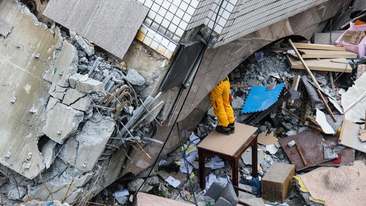 TOPSHOT - A rescue worker clears debris to make way for the recovery of the dead bodies of a Hong Kong Canadian couple from the Yun Tsui building, which is leaning at a precarious angle, in the Taiwanese city of Hualien on February 9, 2018, after the city was hit by a 6.4-magnitude quake late on February 6.
After hours of painstaking search efforts, Taiwanese rescue workers pulled two more bodies from the flattened remains of a hotel February 9, bringing the death toll from a deadly 6.4-magnitude quake to 12.
 / AFP PHOTO / Anthony WALLACE        (Photo credit should read ANTHONY WALLACE/AFP via Getty Images)