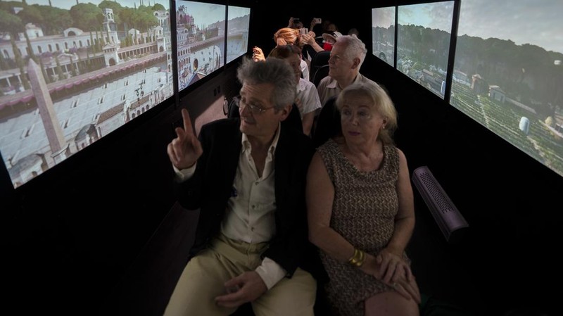 Journalists participating in the first tour of the Imperial Rome - Virtual Reality Bus look at 3D VR images of ancient Rome during the project presentation to the media in downtown Rome, Tuesday, June 21, 2022. The virtual tour of ancient Rome, includes the Roman Forum, the Colosseum, the Palatine Hill, the Circus Maximus, and the Theater of Marcellus, in a 3D immersion with special 