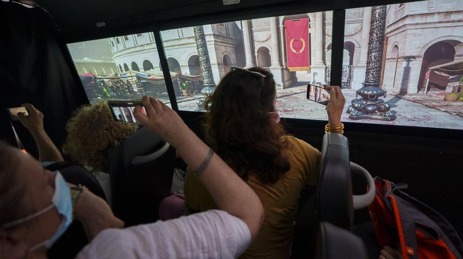 Journalists participating in the first tour of the Imperial Rome - Virtual Reality Bus look at 3D VR images of ancient Rome during the project presentation to the media in downtown Rome, Tuesday, June 21, 2022. The virtual tour of ancient Rome, includes the Roman Forum, the Colosseum, the Palatine Hill, the Circus Maximus, and the Theater of Marcellus, in a 3D immersion with special 